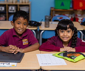 Two students sitting at a desk smiling